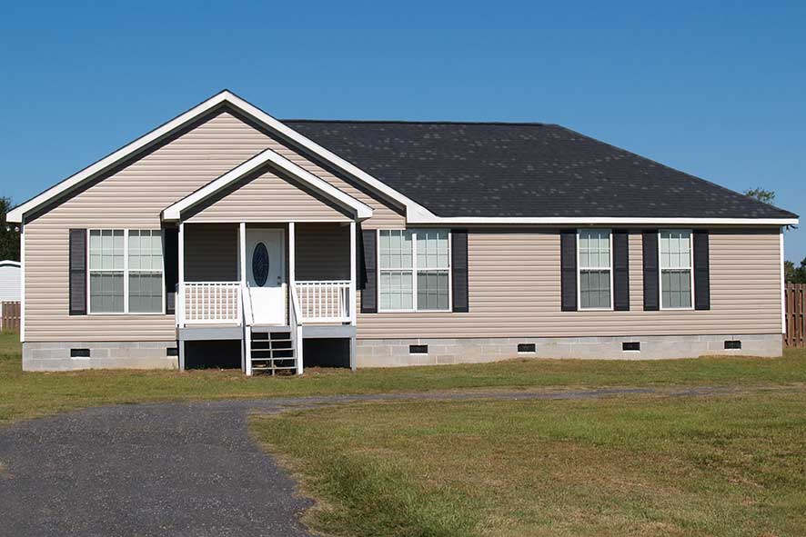 A manufactured home with blue sky and green grass.